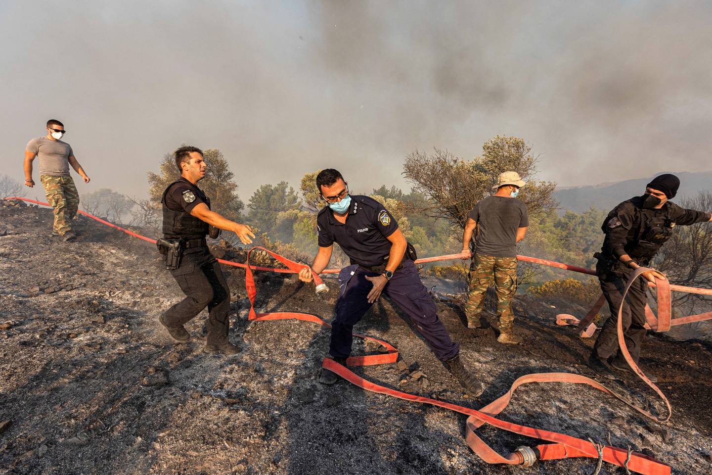 Brannmenn, frivillige og politifolk opererer mens en skogbrann brenner nær landsbyen Asklipieio, på øya Rhodos.