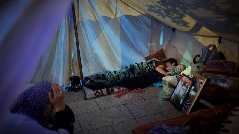 På en madrass rett på bakken, i et telt med hvit teltduk, har Ghenwa Moussa lagt armen rundt sin fem måneder gamle sønn. Hun ligger på magen, han på ryggen. Begge sover. På bakken ved siden av dem står to bilder av guttens far, det ene rammet inn i sort, det andre i gull. FOTO: KYRRE LIEN