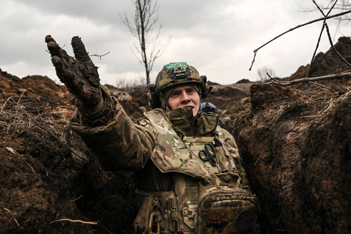TOPSHOT - A Ukrainian serviceman takes cover in a trench near Bakhmut in the Donbas region on March 8, 2023. - After a cold and snowy winter, the arrival of spring with rain and milder temperatures has brought back the mud on the Donbas battle fields.
