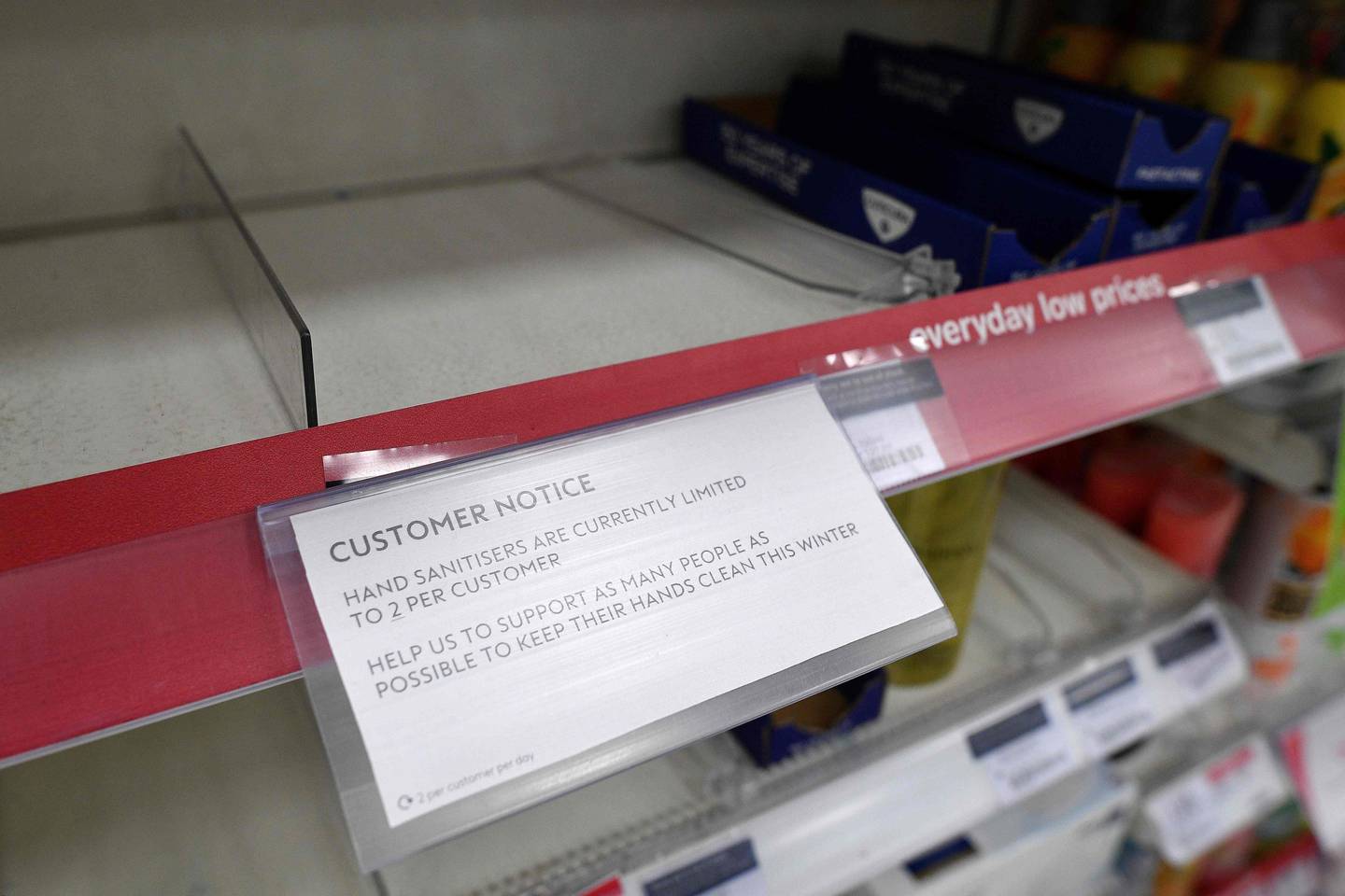 A picture shows a sign, on empty shelves, alerting customers to limited sales of antibacterial hand washes and sanitiser gels, inside a Boots store in London on March 3, 2020. - British pharmacy chain Boots announced Tuesday that it would limit the purchases of hand sanitizer gel, after a spike in sales, following the epidemic of new the  coronavirus. A spokeswoman for the chain told AFP that Boots had seen an increase in sales of hand sanitizer gel but that there were stocks in its warehouses, and that it would now limit purchases to two bottles gel per person to ensure that as many customers as possible can purchase them. (Photo by JUSTIN TALLIS / AFP)