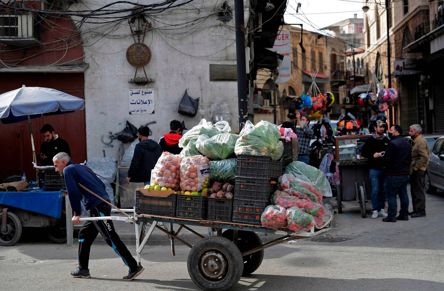 An ambulant vendor pulls his handcart in the Lebanese coastal city of Tripoli, north of Beirut, on January 26, 2021. - Lebanon has imposed a round-the-clock curfew nationwide since January 14, barred non-essential workers from leaving their homes and restricted grocery shopping to deliveries. On paper, its Covid-19 restrictions are among the strictest in the world, but in reality grinding poverty is pushing many back onto the streets to eke out a living. (Photo by JOSEPH EID / AFP)