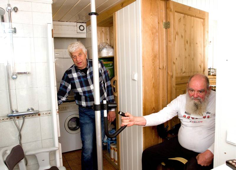 LØSNET FRA VEGGEN: I ukevis har Harald Hauglins dusjbatteri vært løsnet fra veggen. – Farlig, påpeker brukerstyrt personlig assistent Ragnar Larsen, som her stikker hånda inn i det åpne vegglivet for å holde komponenten på plass.