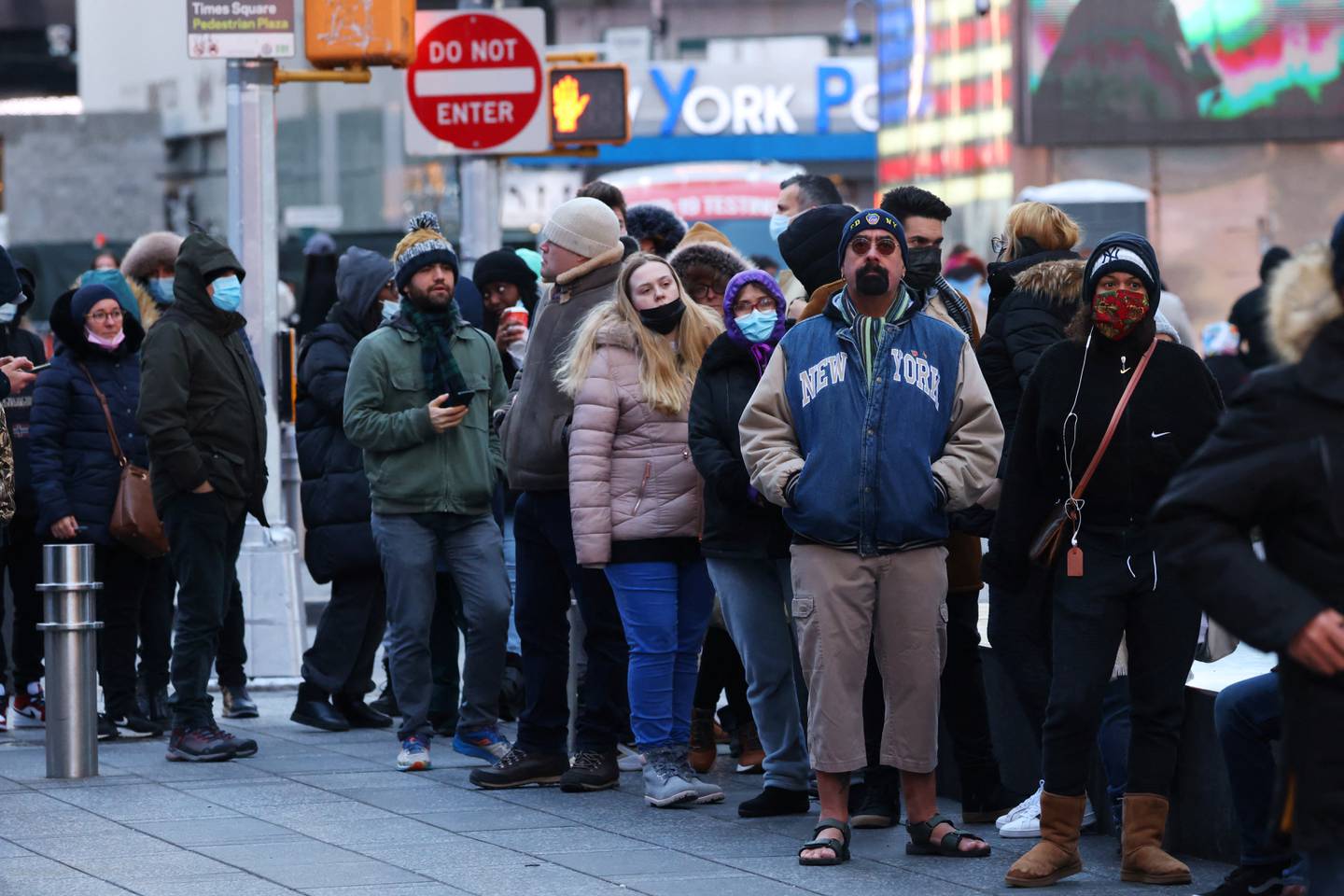 Flere mennesker står på rad, både med og uten munnbind, på Times Square i New York.
