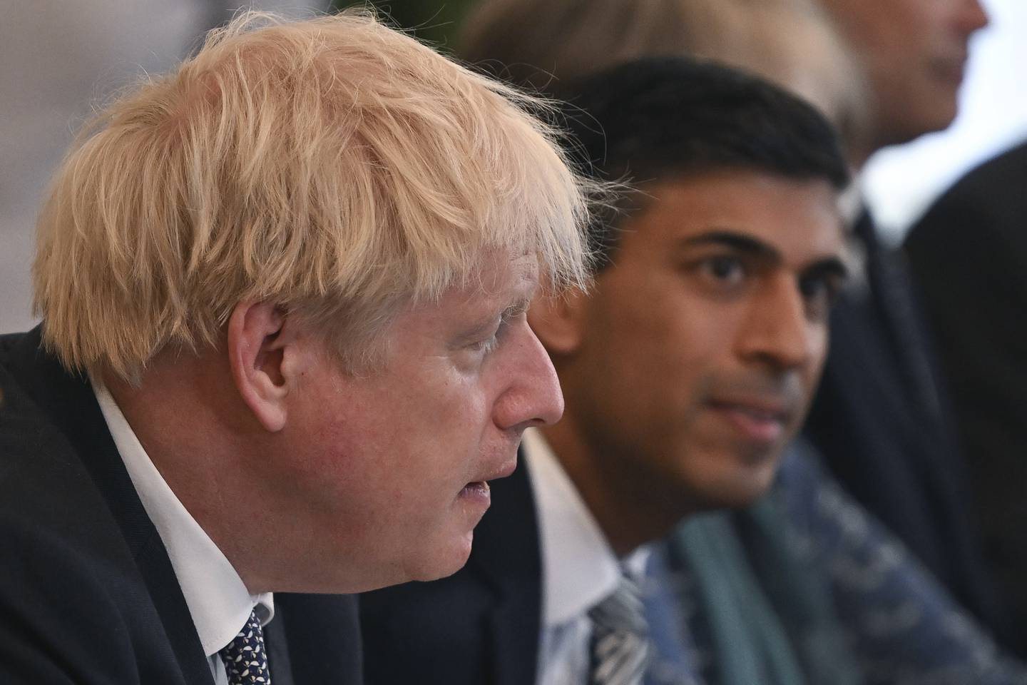 Storbritannias finansminister Rishi Sunak (i bakgrunnen) trekker seg fra regjeringen i protest mot statsminister Boris Johnson. Foto: AP / NTB