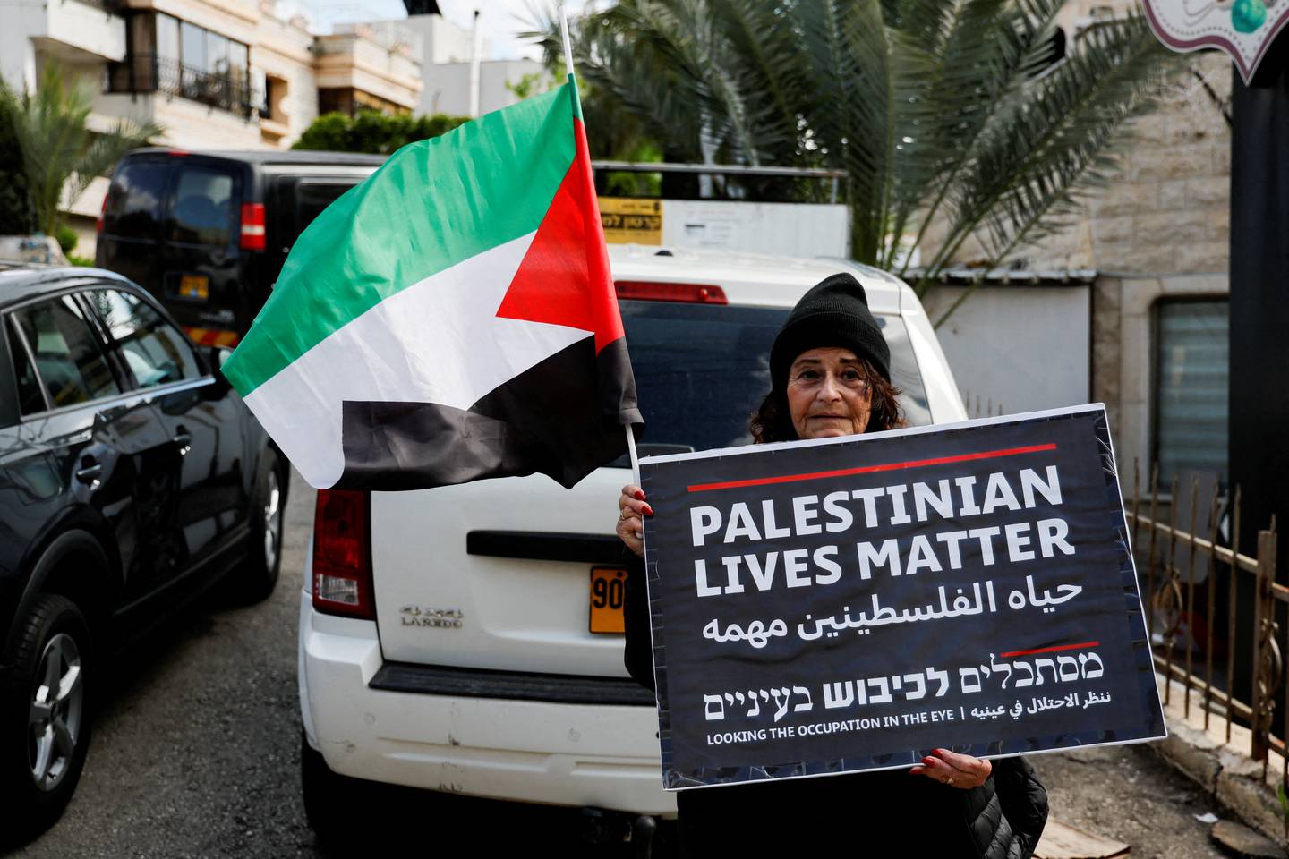 En arabisk-israelsk kvinner holder et palestinsk flagg og en plakat mens hun deltar i en protest 30. mars mot beslaglegging av landområder.