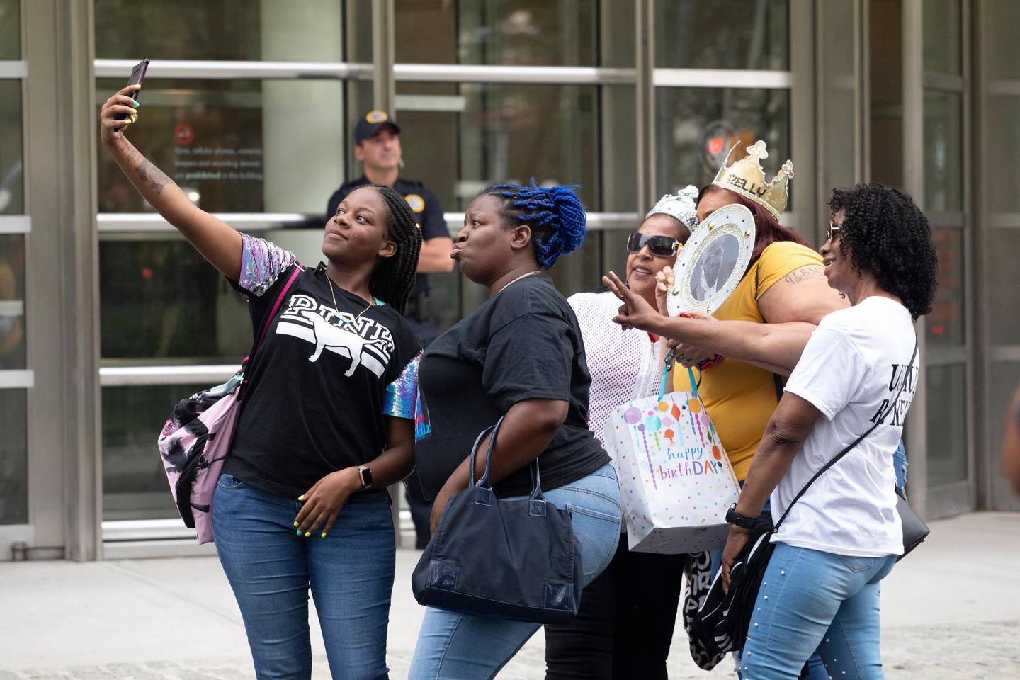 Supporters of R&B performer R. Kelly pose for a selfie outside federal court in Brooklyn before his hearing, Friday, Aug. 2, 2019, in New York. Kelly faces an arraignment on charges he sexually abused women and girls. (AP Photo/Mark Lennihan)