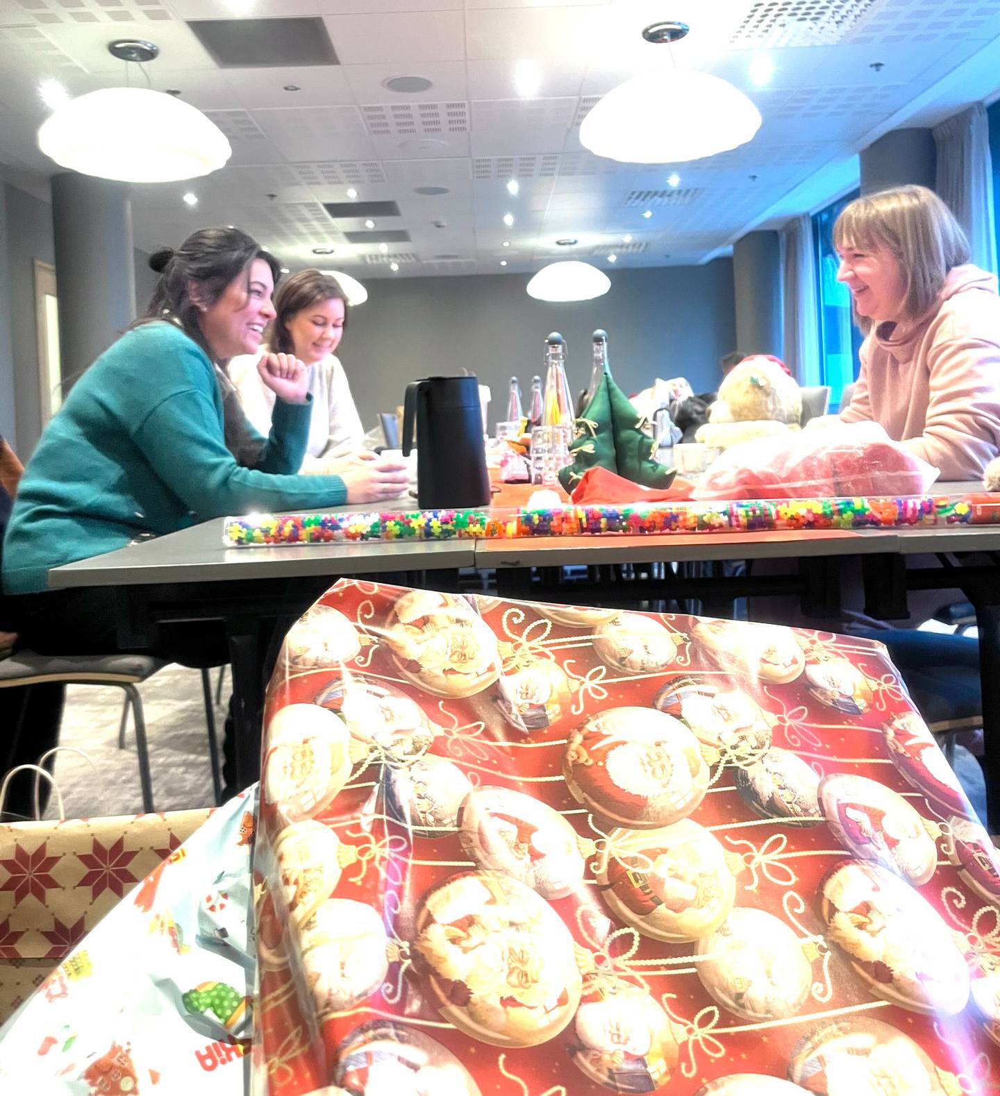 Karen Gjersdal Wolden (bakerst til venstre) og Ingrid Cristina Hess fra Bymisjonen setter pris på hjelpen fra ukrainske Alina (til høyre) når de skal pakke inn alle julegavene de har fått tilsendt.