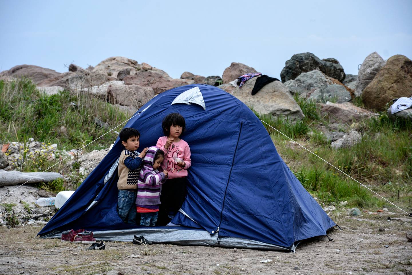Children stand outside a tent in the village of Petra on the northeastern Aegean island of Lesbos, Greece, Friday, March 27, 2020. Some 56 migrants who reached Lesbos in smugglers' boats from Turkey over the past few days have been quarantined in small tents in Petra for the past three days. Under public health measures adopted to hinder the spread of the new coronavirus, Greece places all people arriving from abroad in two-week quarantine. Lesbos' main migrant facility, near the village of Moria, is crammed with about 20,000 people even though it was built for 2,700. (AP Photo/Panagiotis Balaskas)