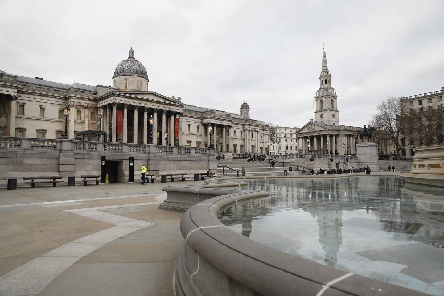 Pedestrians walk in front of the National Gallery in Trafalgar Square in central London on March 17, 2020. - Britain on Tuesday ramped up its response to the escalating coronavirus outbreak after the government imposed unprecedented peacetime measures prompted by scientific advice that infections and deaths would spiral without drastic action. As a result of the outbreak, all events in London's Trafalgar Square, including upcoming celebrations for St George's Day, Vaisakhi and Eid, were cancelled until further notice, and the National Portrait Gallery will also close its doors until further notice from March 18. (Photo by Tolga AKMEN / AFP)