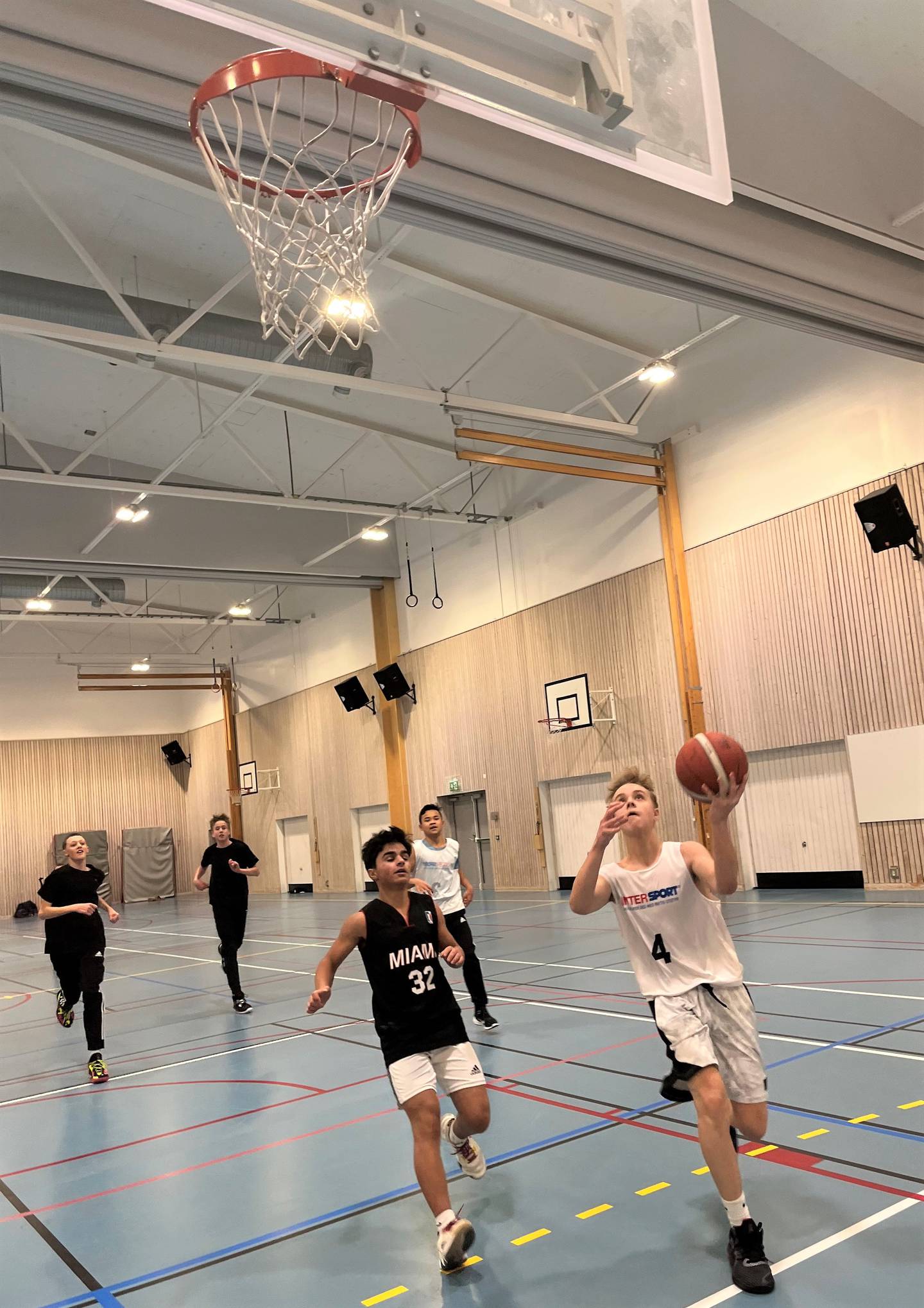 Andreas Løchsen tar sats på trening hos Fredrikstad Basketballklubb i Glemmenhallen – mens rekrutteringen av barn og unge til sporten også har nådd nye høyder de siste årene. Bak Løchsen jager Nicholas Shayar Nikpoor.