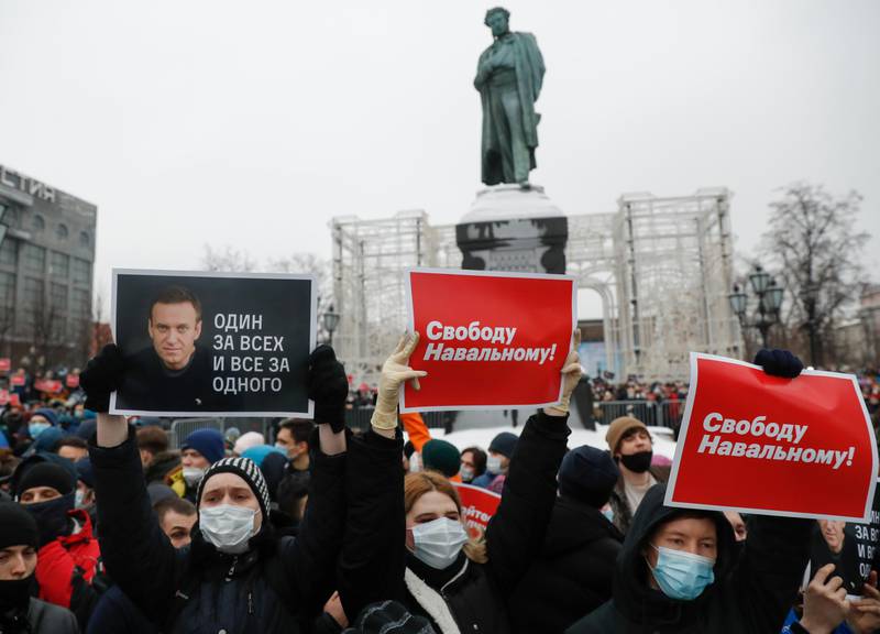 People gather during a protest against the jailing of opposition leader Alexei Navalny in Pushkin square at the statue of Alexander Pushkin in the background in Moscow, Russia, Saturday, Jan. 23, 2021. Protesters hold posters reading "Freedom for Navalny!" and "One for all and all for one" with Navalny's portrait. Russian police on Saturday arrested hundreds of protesters who took to the streets in temperatures as low as minus-50 C (minus-58 F) to demand the release of Alexei Navalny, the country's top opposition figure.  Navalny, President Vladimir Putin's most prominent foe, was arrested on Jan. 17 when he returned to Moscow from Germany, where he had spent five months recovering from a severe nerve-agent poisoning that he blames on the Kremlin. (AP Photo/Pavel Golovkin)