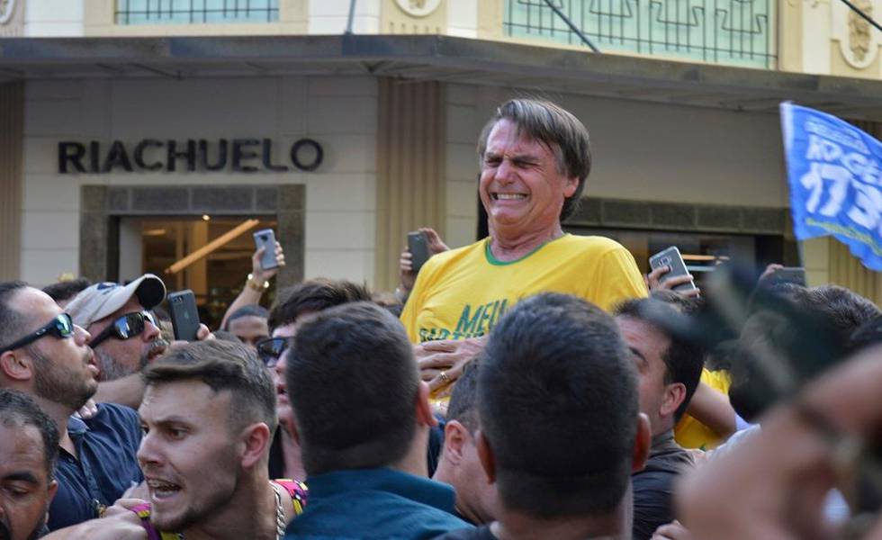 In this Sept. 6, 2018 photo, presidential candidate Jair Bolsonaro grimaces right after being stabbed in the stomach during a campaign rally in Juiz de Fora, Brazil. Bolsonaro, a leading presidential candidate in Brazil, was stabbed during the campaign event, though officials and his son said the injury is not life-threatening. (AP Photo/Raysa Leite)