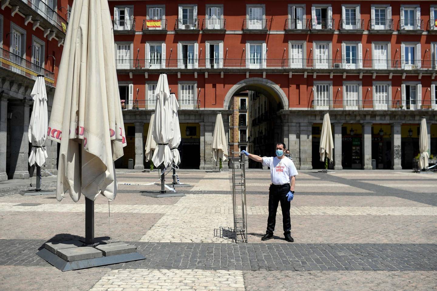 An employee sets up the outdoor seating area of a restaurant on the eve of its reopening at Plaza Mayor in Madrid on May 24, 2020 as the country slowly loosens a strict coronavirus lockdown. (Photo by OSCAR DEL POZO / AFP)