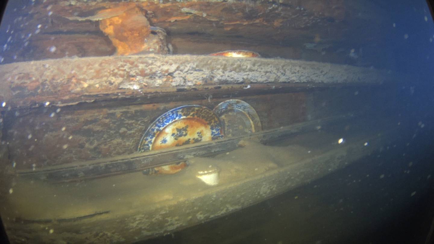 Tallerkener på hyller ved et bord i messa i HMS «Terror» der noen av de lavere rangerte i besetningen hadde sin spiseplass. Bilde fra skipet under vann i Terror-bukta, utenfor King Williamsøya.