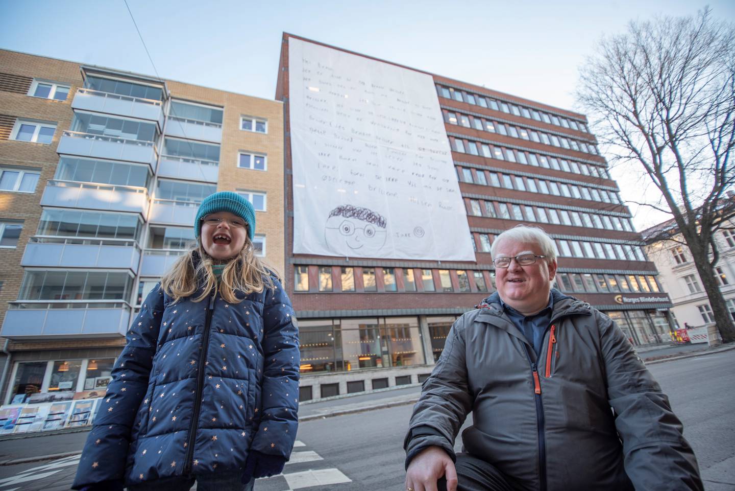 Ruby syntes det var stor stas å få brevet sitt hengt opp på bygget til Norges Blindeforbund. Her sammen med forbundsleder, Terje André Olsen.