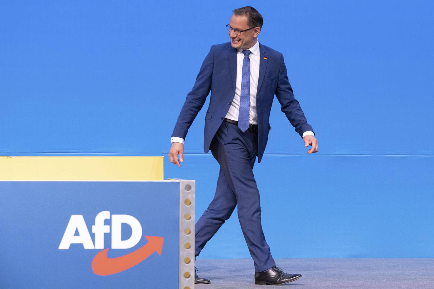 Tino Chrupalla går bak et podium med AfD-logo.