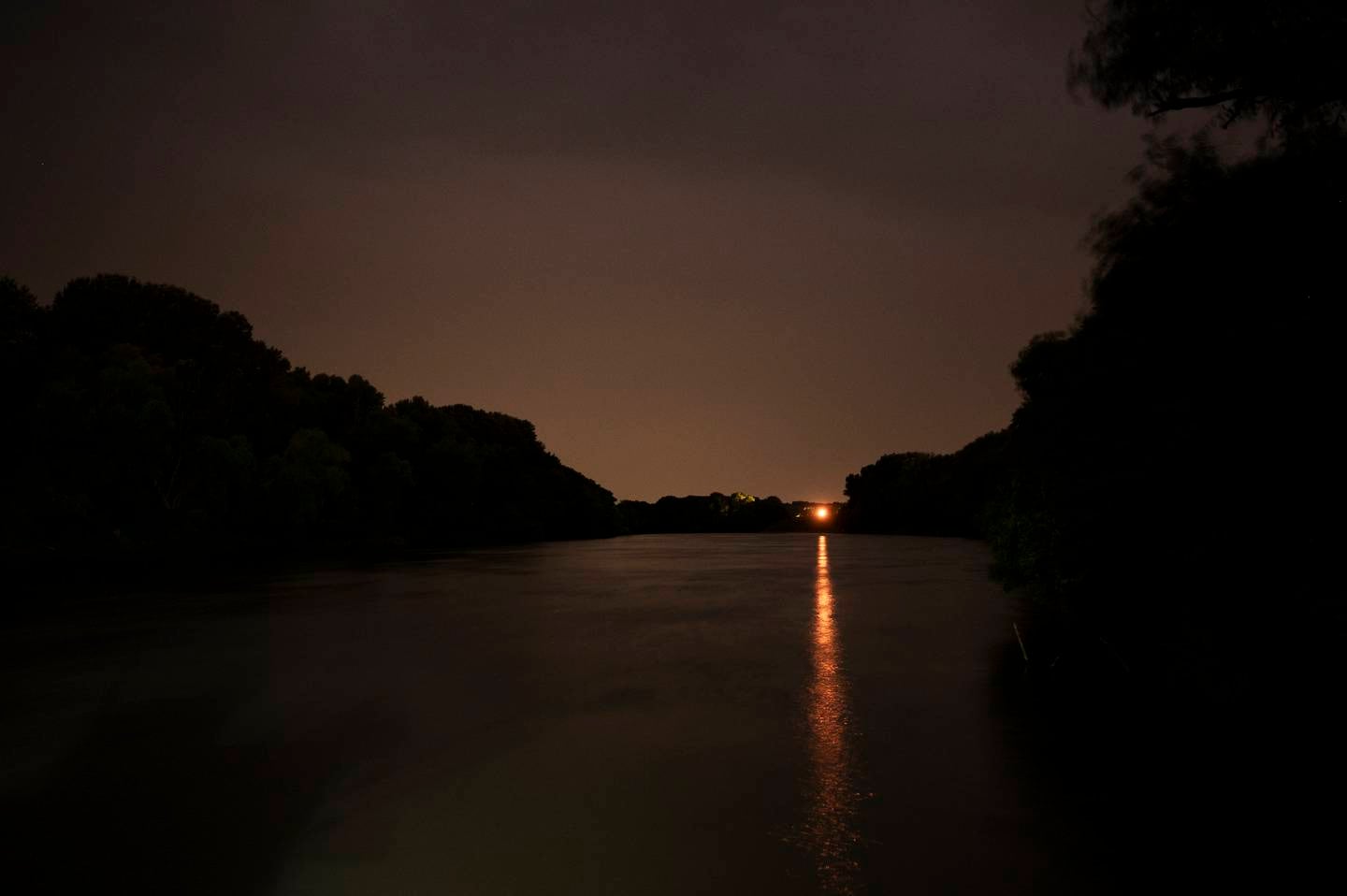 Lights shine at night on the Tisza River near Tiszaroff, Hungary, Tuesday, Aug. 1, 2023. Since its start in 2013, participants in the annual Plastic Cup competition — which offers a prize for those who collect the most trash each year — have gathered more than 330 tons (around 727,000 pounds) of waste from the Tisza and other Hungarian waters. (AP Photo/Denes Erdos)