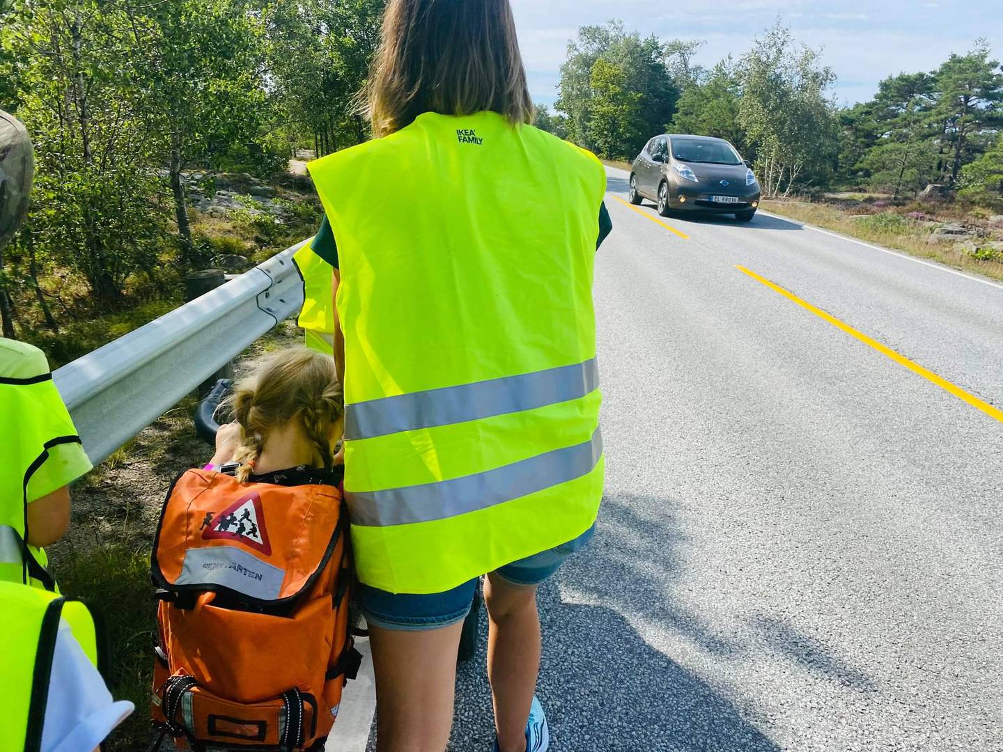 Ei lita jente med førskolesekk og en mor i gul vest langs fylkesvei 108 på Hvaler