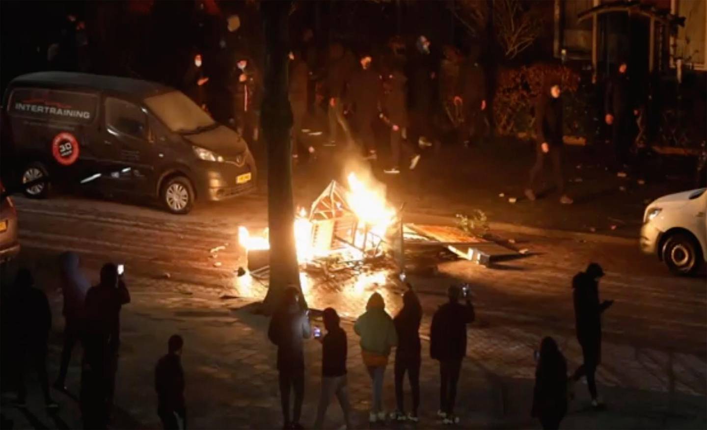 In this grab taken from video on Monday, Jan, 25, 2021, people use their phones to film items burning on a fire started by rioters, in Haarlem, Netherlands. Groups of youths have confronted police in several Dutch cities defying the countrys coronavirus curfew and throwing fireworks. Police in the port city of Rotterdam used a water cannon and tear gas in an attempt to disperse a crowd of rioters Monday night. (Mizzle Media via AP)