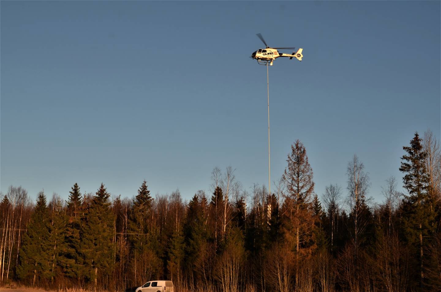 Med stødig hånd manøvrer pilot Kalle Schmidt helikopter og sag langs strømlinjene. Med en total 30 meter lang leddet stang under.