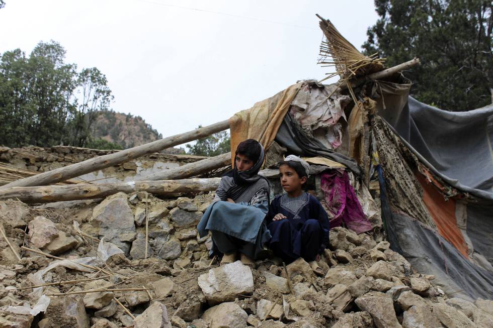 Afghanske gutter sitter ved sitt ødelagte hus i Spera-distriktet i den sørvestlige delen av provinsen Khost onsdag. Foto: AP / NTB