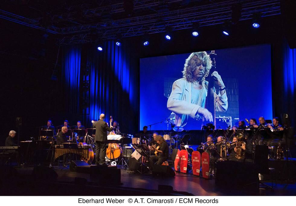 Helge Sunde dirigerer stort band med Eberhard Weber live på video bak. FOTO: RALF DOMBROVSKI/ECM