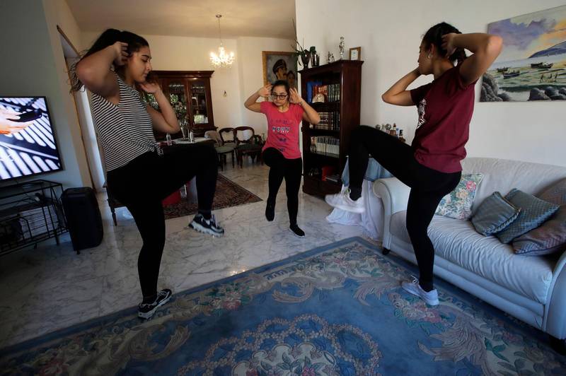 Selene Mirra, center, trains with her sisters, Aurora, left, and Sabrina in the living room of their home in Rome on April 4, 2020. Selene, an athlete on the Italian Down syndrome synchronized swimming team, continues her training despite the Tokyo 2020 postponement due to COVID-19. (AP Photo/Alessandra Tarantino)