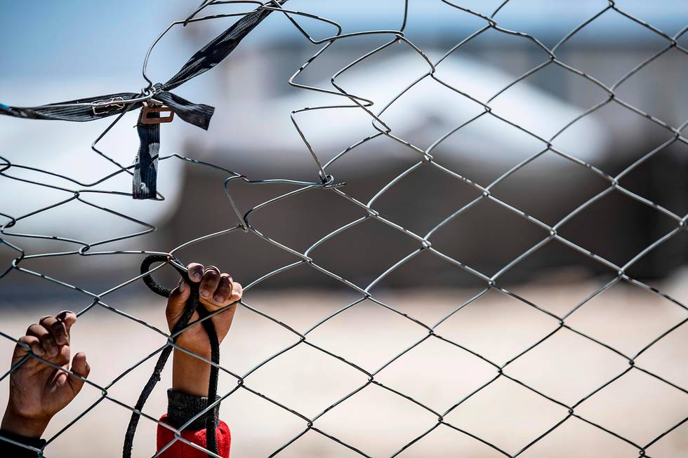 TOPSHOT - This picture shows the hands of a Syrian child hooked at a fence at the al-Hol camp in al-Hasakeh governorate in northeastern Syria, on August 08, 2019. - The Kurdish authorities have repeatedly appealed to the international community for support to manage Al-Hol and other camps housing displaced civilians and suspected IS family members. (Photo by Delil SOULEIMAN / AFP)
