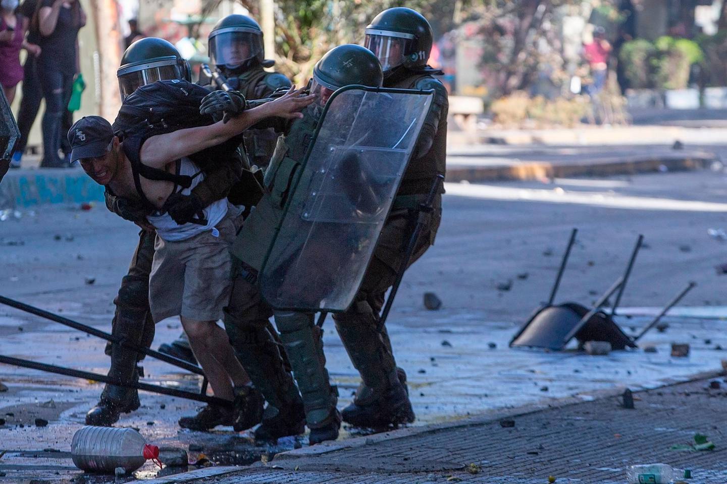 TOPSHOT - Riot police detain a demonstrator during clashes in Santiago on October 24, 2019 after a week of street violence which erupted against a now suspended metro fare hike but spiralled into general discontent. - A general strike in Chile went into its second day following a week of street protests for general discontent at low salaries and pensions, high costs of health care and education, and a yawning gap between rich and poor, that left 18 dead. (Photo by Claudio REYES / AFP)