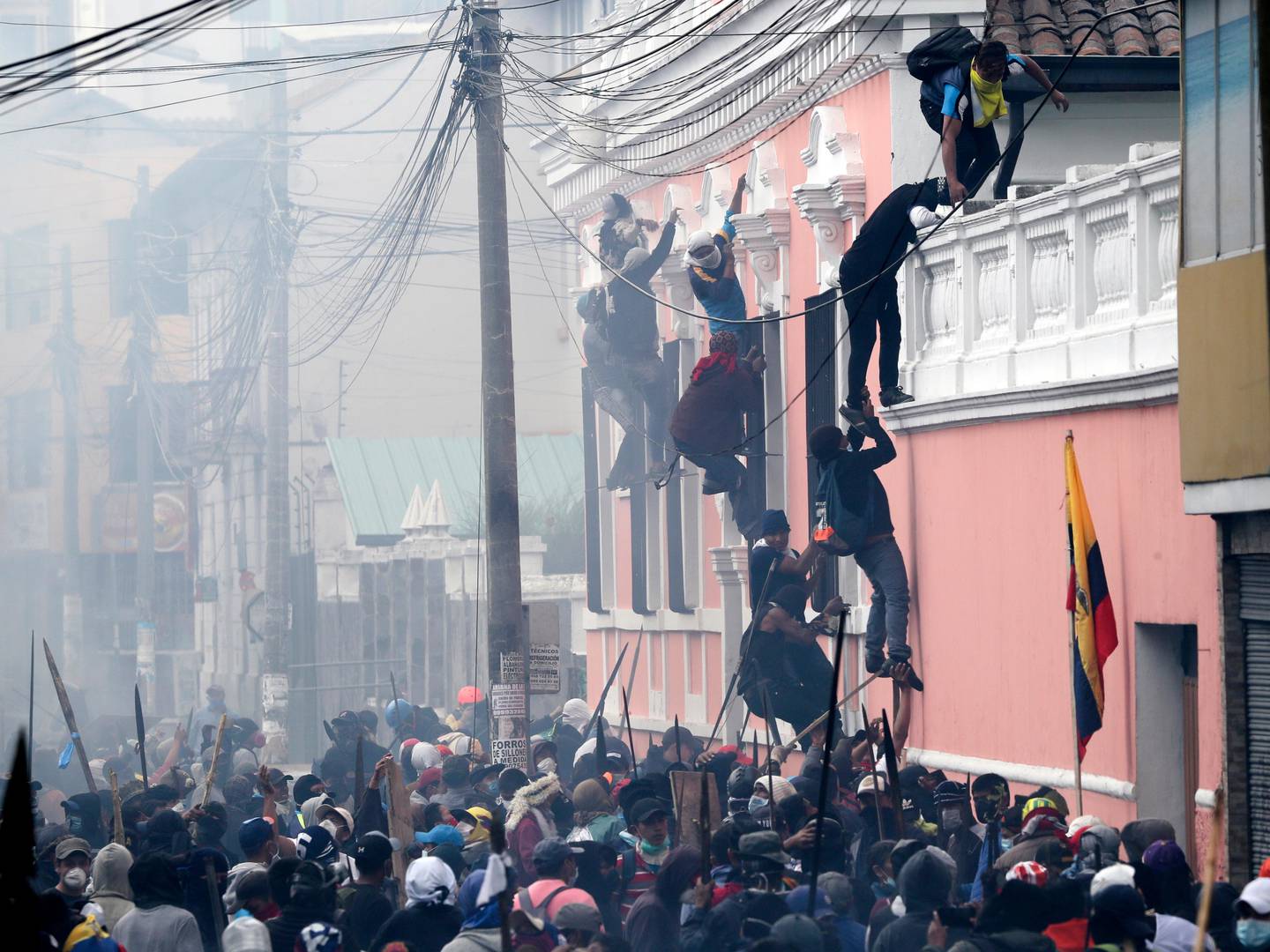 Anti-government demonstrators scale the facade of a residence to reach the rooftop, looking for a better vantage point to battle with police, in Quito, Ecuador, Friday, Oct. 11, 2019. Protests, which began when President Lenin Moreno's decision to cut subsidies led to a sharp increase in fuel prices, persisted for days. (AP Photo/Dolores Ochoa)