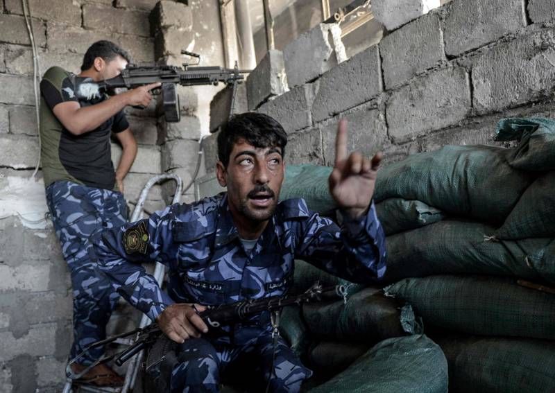 Et medlem av Iraks ledende antiterrorgruppe lader et maskingevær mens en annen legger seg i dekning i en del av offensiven mot gamlebyen i Mosul, mandag denne uka.
