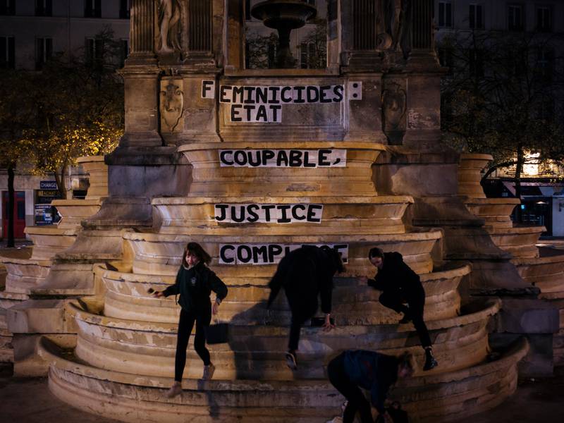 In this photo taken in the early hours of Monday Nov. 4, 2019, from left to right, Pauline, Clivia, France and Lea paste a slogan on a fountain reading " Femicides : guilty state, accomplice justice" in central Paris. About 300 women across France pasted slogans at the same time overnight from Sunday to Monday on courthouses in 27 different French cities to denounce the alleged inaction of the French government and demanding justice about femicides. (AP Photo/Kamil Zihnioglu)