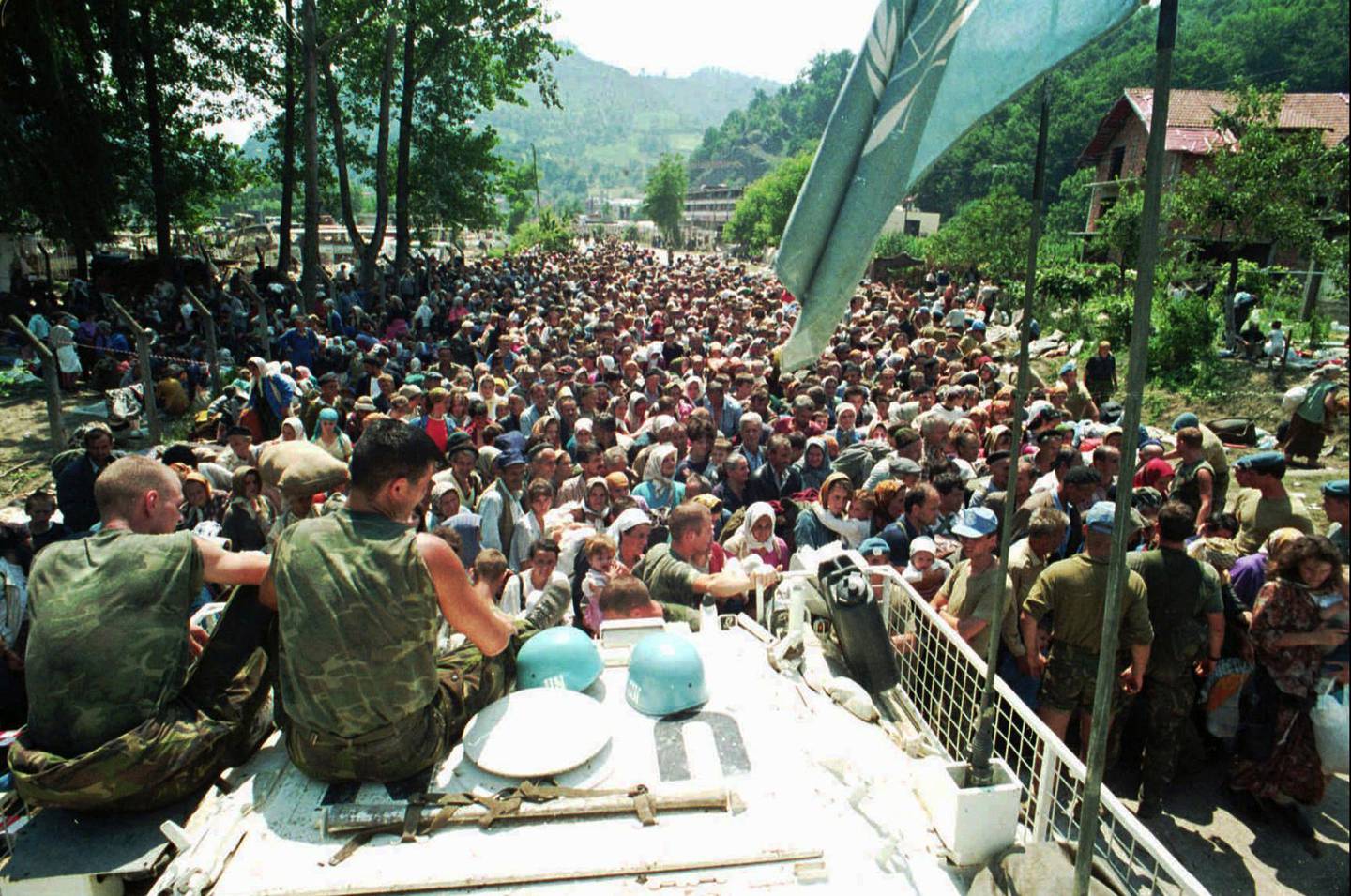 FILE - In this July 13, 1995 file photo, Dutch U.N. peacekeepers sit on top of an armored personnel carrier while Muslim refugees from Srebrenica, eastern Bosnia, gather in the village of Potocari, just north of Srebrenica. The Dutch Supreme Court is ruling Friday July 19, 2019 in a long-running legal battle over whether the Netherlands can be held liable in the deaths of more than 300 Muslim men who were murdered by Bosnian Serb forces during the 1995 Srebrenica massacre. (AP Photo/File)