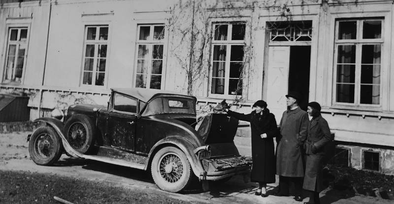 Ragni Friis Berg med sin mann Yngvar P. Berg og søster Gunvor på gårdsplassen. Berg var lidenskapelig interessert i biler.