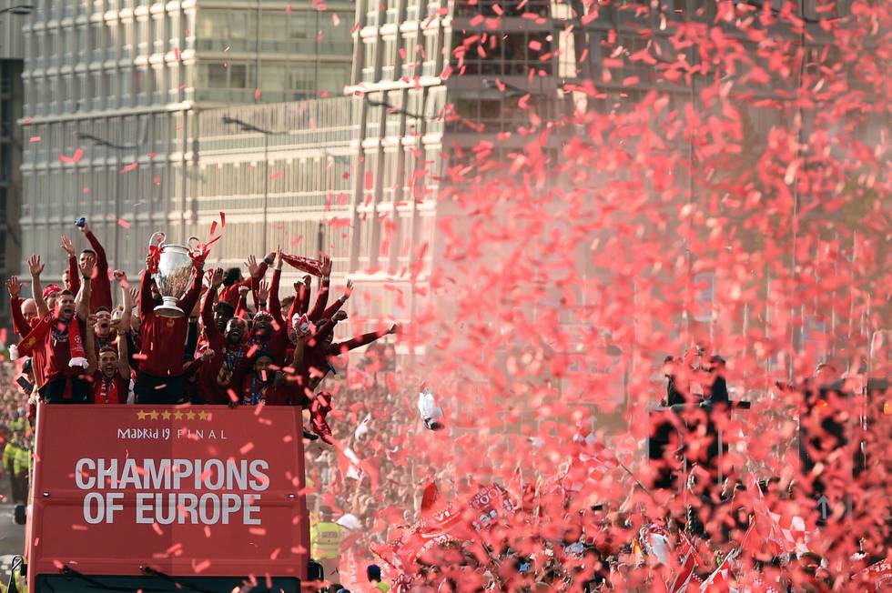 TOPSHOT - Liverpool's German manager Jurgen Klopp (C) holds the European Champion Clubs' Cup trophy as he stands with his players during an open-top bus parade around Liverpool, north-west England on June 2, 2019, after winning the UEFA Champions League final football match between Liverpool and Tottenham. - Liverpool's celebrations stretched long into the night after they became six-time European champions with goals from Mohamed Salah and Divock Origi to beat Tottenham -- and the party was set to move to England on Sunday where tens of thousands of fans awaited the team's return. The 2-0 win in the sweltering Metropolitano Stadium delivered a first trophy in seven years for Liverpool, and -- finally -- a first win in seven finals for coach Jurgen Klopp. (Photo by Oli SCARFF / AFP)