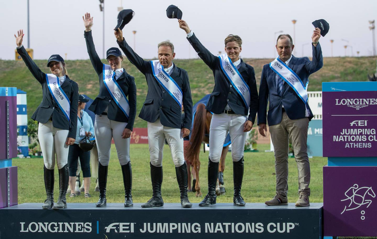 Victoria Gulliksen (L) Hege C Tidemandsen (2L) Geir Gulliksen (3L) and and Johan-Sebastian Gulliksen (4L) with Chef d'equine Mikael Kolind (R) with their caps off on the podium as they celebrate winning the Longines FEI Jumping Nations Cup of Greece in the Markopoulo Olympic Stadium Equestrian Center in Markopoulo, Greece, 28 July 2019. Norway won the event and Portugal came in second.