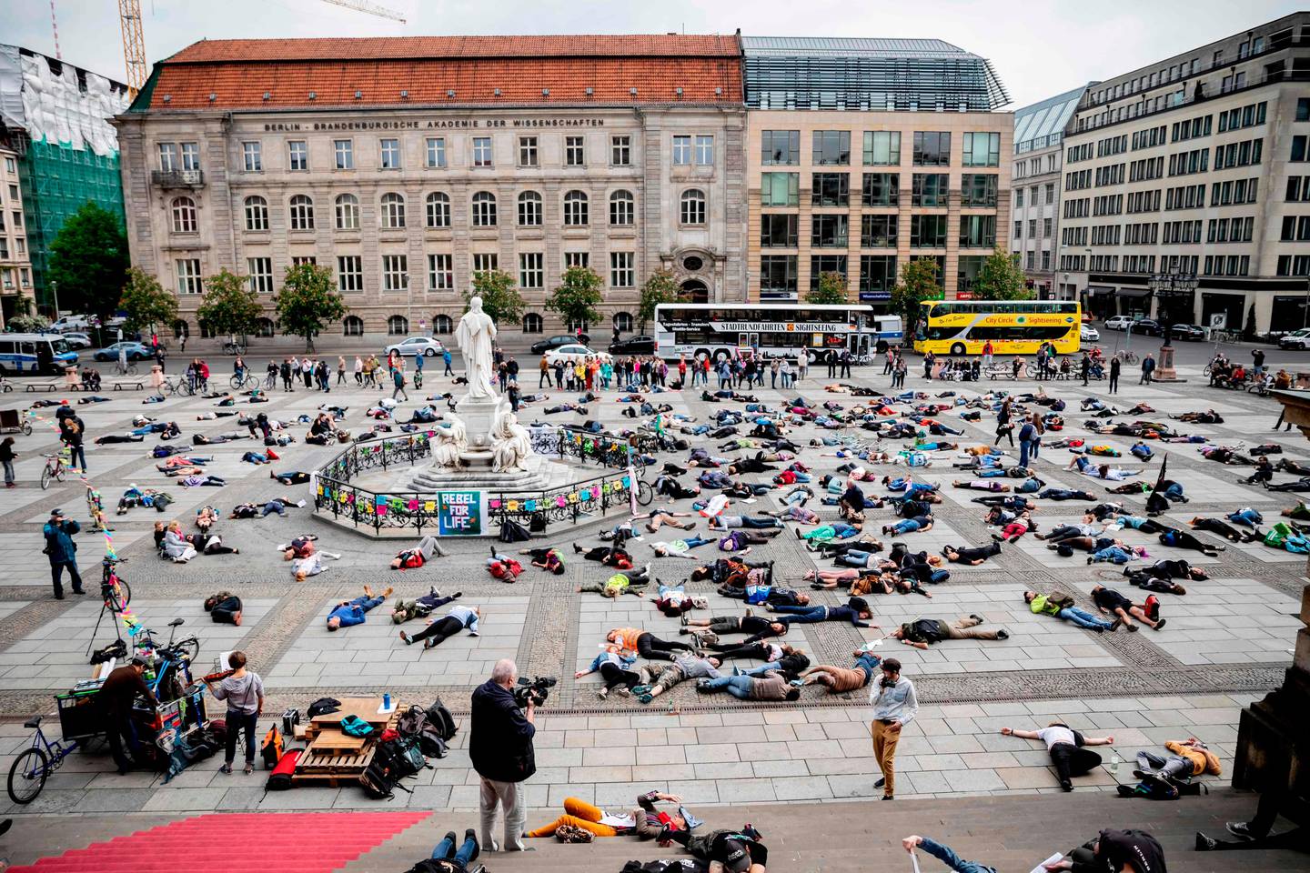 Extinction Rebellion (XR) climate change activists lie on the floor to symbolize a "mass die" at the Gendarmenmarkt square in Berlin on April 27, 2019. - Extinction Rebellion (XR) is an international movement that uses non-violent civil disobedience to achieve radical change in order to minimize the risk of human extinction and ecological collapse. (Photo by Christoph Soeder / dpa / AFP) / Germany OUT
