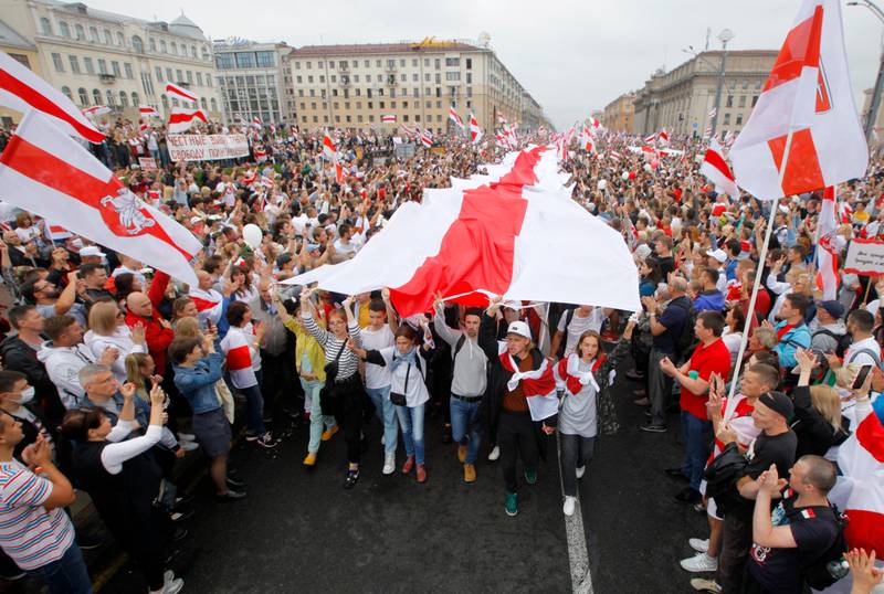 FILE - In this Aug. 23, 2020, file photo, demonstrators carry an old Belarusian national flag as thousands gather for a protest at Independence Square in Minsk, Belarus. With anti-government protests in Belarus now in their third week  including rallies that brought out an estimated 200,000 people in Minsk for the last two Sundays  authoritarian President Alexander Lukashenko is moving to squelch the demonstrations gradually with vague promises of reforms mixed with threats, court summonses and the selective jailing of leading activists. (AP Photo/Dmitri Lovetsky, File)