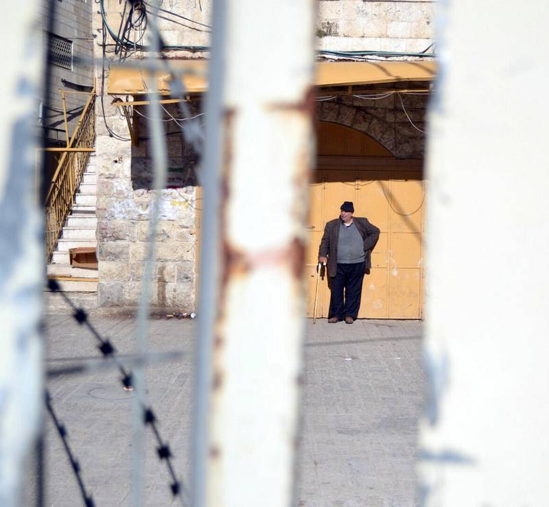 En palestiner sett gjennom sperren som deler Hebron i to, en israelskkontrollert og en palestinsk del.