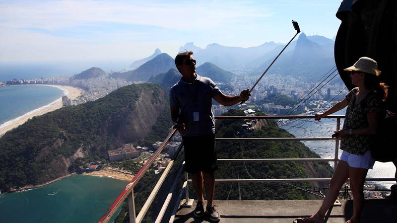 En mann tar en selfie med mobiltelefon på en selfiestang på toppen av Sukkertoppen i Rio de Janeiro. FOTO: ERIK JOHANSEN/NTB SCANPIX