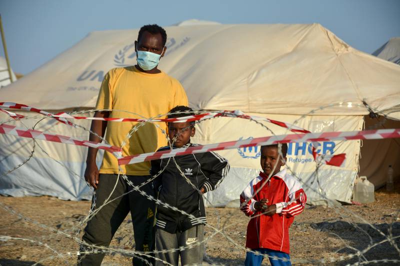 Migrants stand inside the new temporary refugee camp in Kara Tepe, on the northeastern island of Lesbos, Greece, Saturday, Sept. 19, 2020. Police on the Greek island of Lesbos on Friday resumed relocating migrants rendered homeless when fires ravaged the country's largest refugee camp amid a local COVID-19 outbreak. (AP Photo/Panagiotis Balaskas)