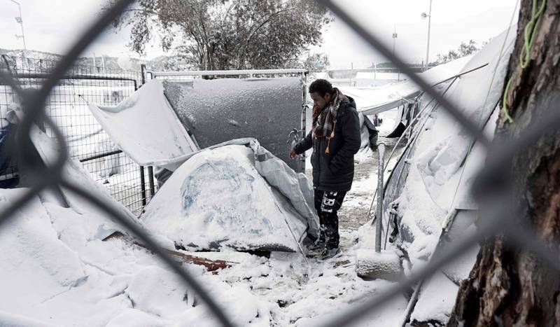 En asylsøker ved siden av det snødekte teltet sitt i Moria flyktningleir på den greske øya Lesbos i januar. Teltleirene skulle være midlertidige ordninger, men asylsøkerne kommer seg ikke videre i Europa og mange har vært strandet i de greske leirene i over ett år. Leveforholdene er uakseptable, ifølge Amnesty.