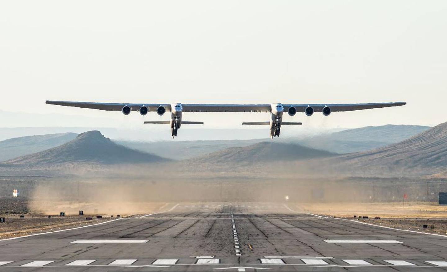 This handout photograph obtained courtesy of Stratolaunch shows the Stratolaunch plane flying above the California desert, April 13, 2019, the first test flight of the US company's gigantic aircraft whose wingspan is almost half that of an Airbus A380. - The strange aircraft, built by the legendary aeronautical engineering company Scaled Composites in the Mojave Desert, has two fuselages and is powered by six Boeing 747 engines.  It must theoretically be used to carry and drop at altitude a small rocket that will then light its engine, and will propel to space to place satellites in orbit. This is a more flexible method of accessing the space than vertical rocket takeoffs, as a large take-off runway would suffice. (Photo by Handout / Stratolaunch Systems Corp / AFP) / == RESTRICTED TO EDITORIAL USE  / MANDATORY CREDIT:  "AFP PHOTO /  STRATOLAUNCH" /  NO MARKETING / NO ADVERTISING CAMPAIGNS /  DISTRIBUTED AS A SERVICE TO CLIENTS  ==