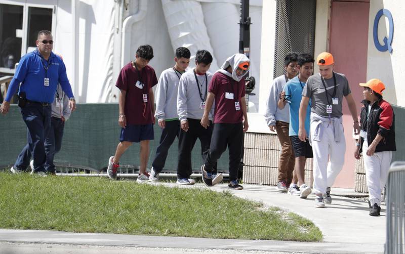FILE- In this July 15, 2019 file photo, migrant children walk on the grounds of the Homestead Temporary Shelter for Unaccompanied Children, in Homestead, Fla.The Trump administration announced Monday, Oct. 28, 2019 that it is shutting down operations at one of the largest U.S. facilities for child migrants that had come under intense criticism from advocates and lawmakers. The U.S. Department of Health and Human Services said it reduced bed capacity from 1,200 to zero at the Homestead, Florida site. About 2,000 workers were being let go. (AP Photo/Lynne Sladky)