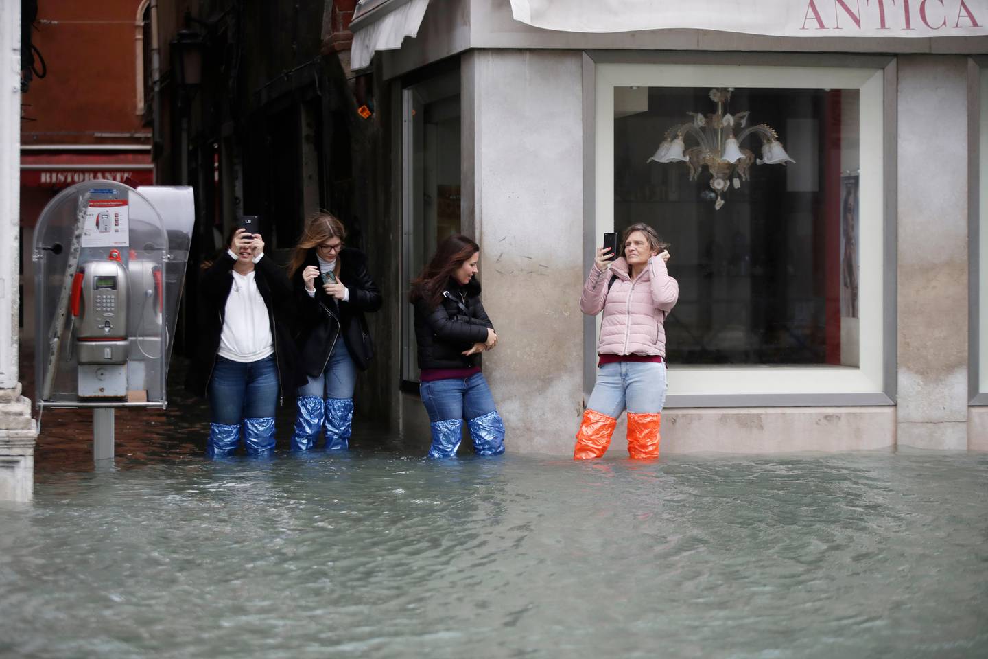 Tourists take pictures of a flooded Venice, Italy, Friday, Nov. 15, 2019. The high-water mark hit 187 centimeters (74 inches) late Tuesday, Nov. 12, 2019, meaning more than 85% of the city was flooded. The highest level ever recorded was 194 centimeters (76 inches) during infamous flooding in 1966. (AP Photo/Luca Bruno)