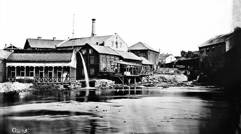 På venstre elvebredd sees bedriftens badehus for ansatte og familie. I 1840-50-åra vurderte man å mudre opp elva og anlegge havn her. Litt seinere begynte utparselleringa av tomter på Grünerløkka/New York.