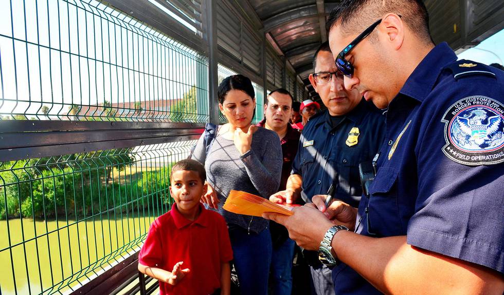 tilbake: Amerikanske grensemyndigheter venter på å overlevere en gruppe asylsøkere til Mexico ved brua mellom Laredo i Texas og Nuevo Laredo i nabolandet. Migrantene er en del av den såkalte «Bli i Mexico»-politikken, og de skal vente i Mexico på å få asylsøknadene sine i USA behandlet. FOTO: SALVADOR GONZALES/NTB SCANPIX