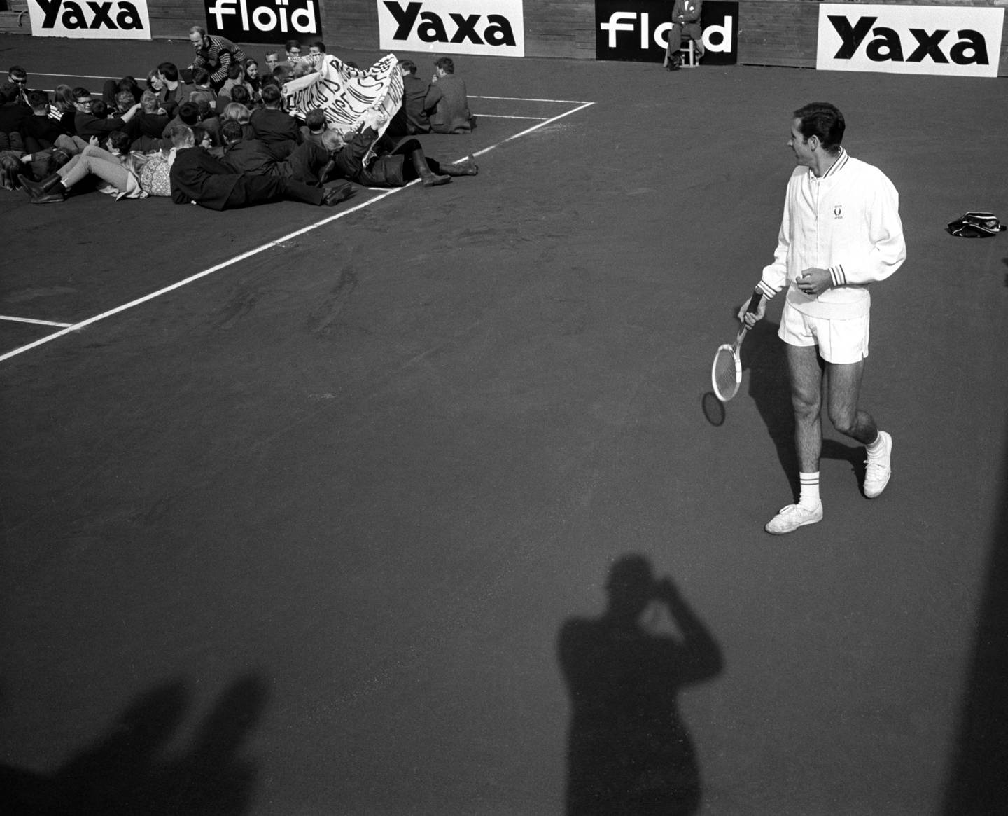 Tennisspiller titter bort på demonstrantene som ligger på banen.
