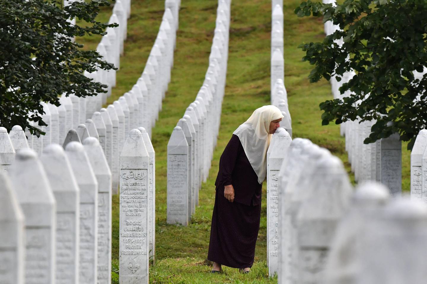 Bosnian Muslim woman Mejra Djogaz, 71, survivor of Srebrenica 1995 massacre, kisses her sons' tombstones, Omer, 19, and Munib, 21, her two sons killed in the massive killing of Srebrenica during Bosnia's 1992-95 war, at Potocari memorial center, near Srebrenica on July 3, 2020. - Eight thousands Muslim men and boys were killed by Serb forces in the eastern enclave towards the end of Bosnia's 1992-95 war, an atrocity deemed a genocide by international courts, whose remains were found in mass graves after the conflict, were buried a decade ago in the memorial centre where more than 6,600 victims of the victims lie.
Another 237 have been laid to rest at other sites. But more than 1,000 people have never been found, an acute source of pain for survivors. (Photo by ELVIS BARUKCIC / AFP)