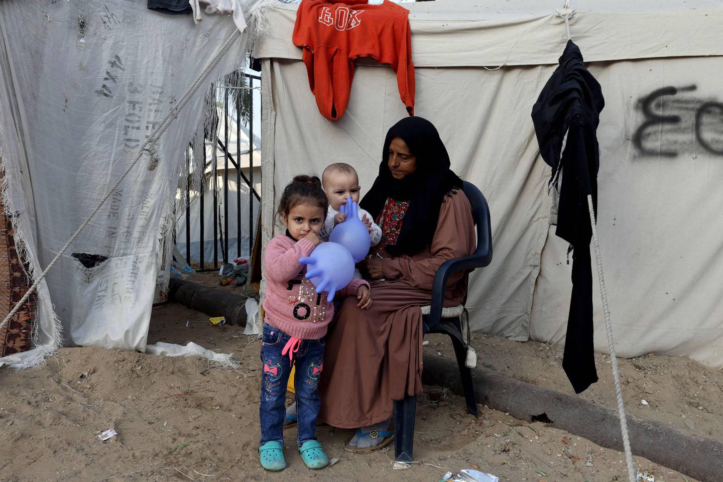 En palestinsk kvinne som er internt fordrevet sitter med barn utenfor et telt i Rafah, sør på Gazastripen.